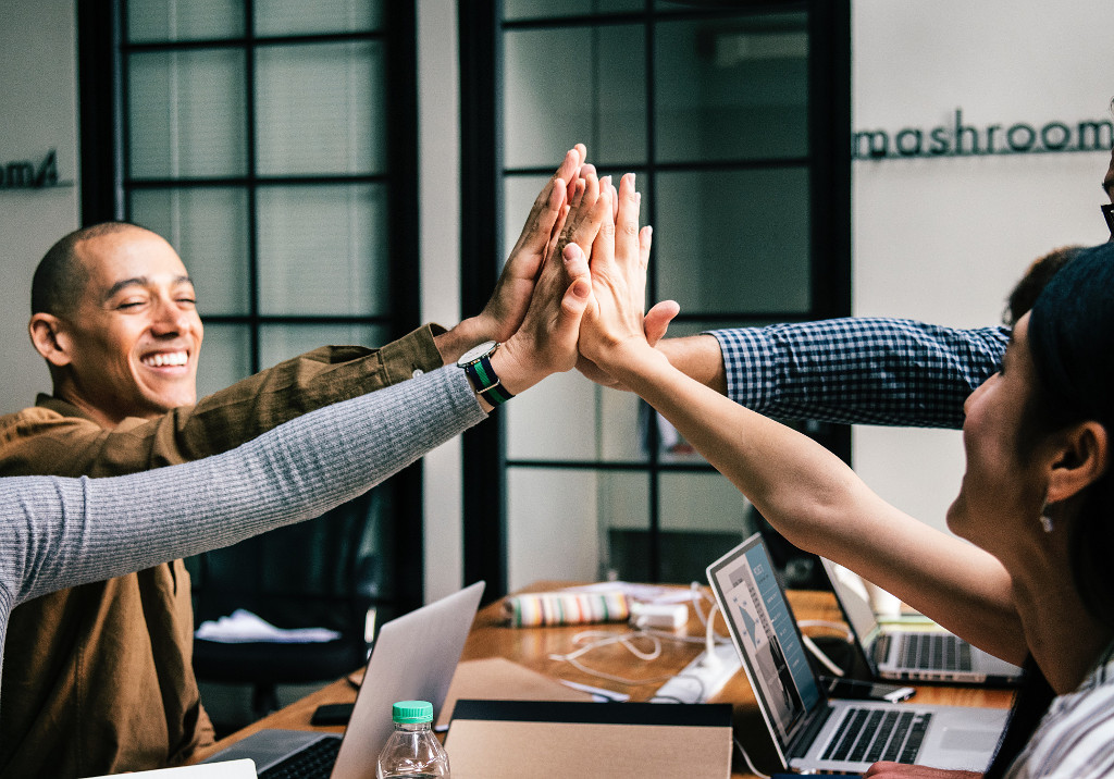 Group of people high-fiving over a desk